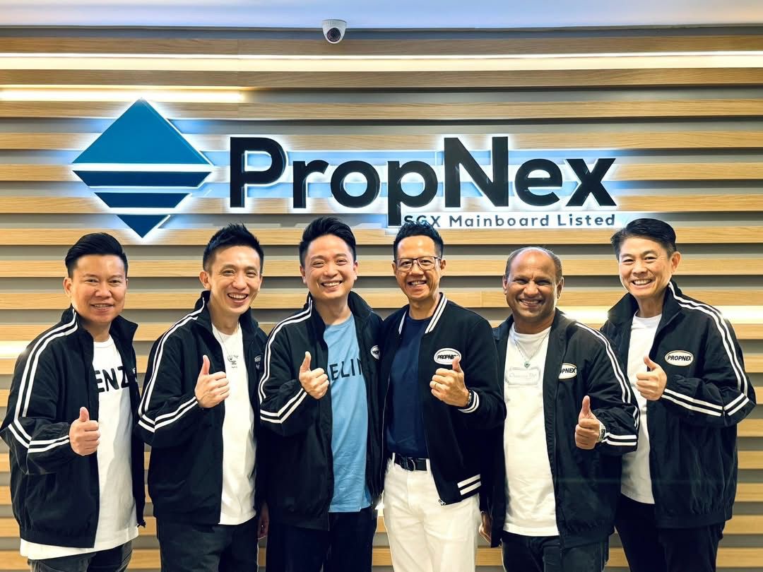Adrian standing with five senior PropNex colleagues in front of the PropNex SGX Mainboard Listed wall